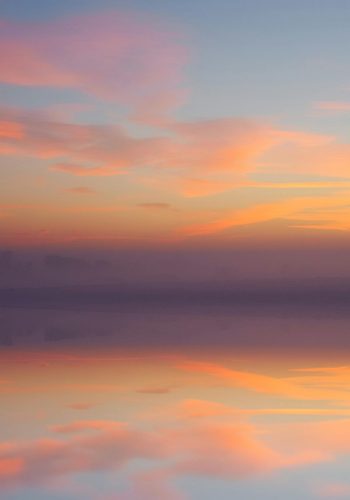 pexels-photo-1477836-1477836 Tranquil sunrise with colorful sky reflecting over calm waters and a lone tree.
